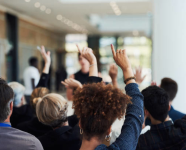 Shot of a group of businesspeople raising their hands to ask questions during a conference