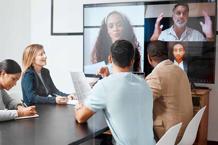 Cropped shot of a diverse group of businesspeople sitting in the boardroom during a meeting with their international colleagues via video chat